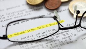 Brille und Geldmünzen auf Grundsicherungsbescheid 