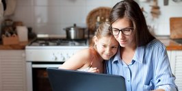 Mutter und Tochter mit Laptop am Küchentisch