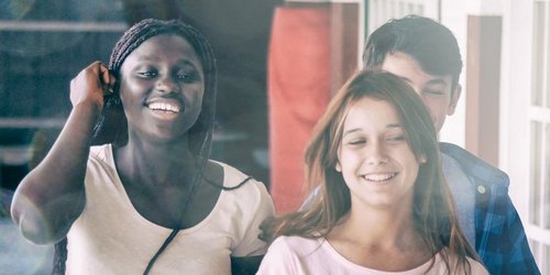 Drei Mädchen und ein Junge laufen fröhlich durch einen Schulflur