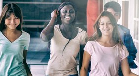 Drei Mädchen und ein Junge laufen fröhlich durch einen Schulflur