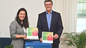 Regionalverbandsdirektor Peter Gillo und vhs-Direktorin Dr. Carolin Lehberger halten das neue Semesterprogramm in Händen. 