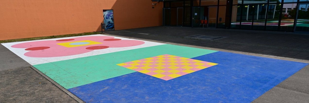 Ein buntes Feld auf einem Schulhof als Hitzeschutz und Spielmöglichkeit