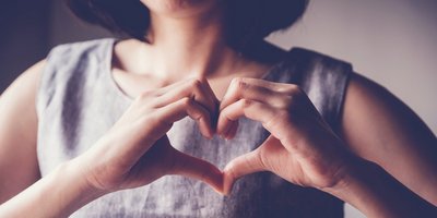 Eine junge Frau formt mit den Händen ein Herz