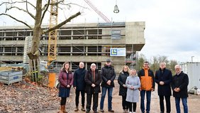 Der Bauherr Regionalverbandsdirektor Peter Gillo (3.v.r.) und Schulleiter Norbert Moy (3.v.l.) freuten sich beim Richtfest gemeinsam mit Bildungsstaatssekretärin Jessica Heide (4.v.r.), dem Völklinger Oberbürgermeister Stephan Tautz (r.), dem Geschäftsführer von arus GmbH, Willi Latz (2.v.r.) und weiteren Vertreterinnen und Vertretern des Regionalverbands und des Ministeriums für Bildung und Kultur. Alle stehen vor dem Rohbau.