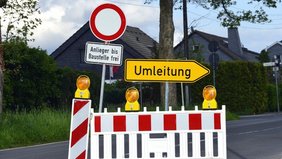 Umleitungsschild aufgrund einer Straßenbaustelle, die mitten auf der Straße aufgestellt ist inklusive Absperrung