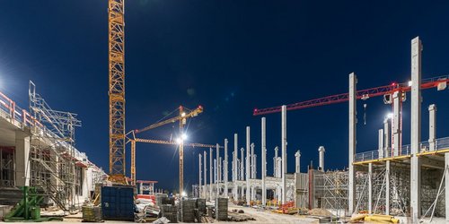 Baustelle mit diversen Baukränen bei Nacht