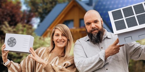 Eine Frau hält eine Miniaturnachbildung einer Wärmepumpe in die Luft. Neben ihr steht ein Mann, der eine Miniaturnachbildung eines Hauses mit einer Solaranlage auf dem Dach präsentiert. Beide abgelichtet vor einem Einfamilienhaus im Grünen.