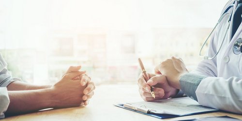 Die Händer von Arzt und Patient auf einem Tisch während eines Beratungsgespräches