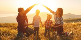 Eltern bilden ein schützendes Haus mit den Händen um ihre Kinder