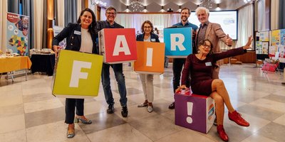 Sechs Personen, die folgende Buchstaben auf Würfeln in die Höhe halten: F, A, I, R und ein Ausrufezeichen. Dies sind von links: Regionalverbandsdirektorin Dr. Carolin Lehberger, ehemaliger Regionalverbandsdirektor Peter Gillo, ehemalige Fairtrade-Beauftragte Heike Erbelding, Fairtrade-Beauftragter Stephan Zander, Ehrenbotschafter Fairtrade-Deutschland Manfred Holz und Fleurance Laroppe von der Fairtrade Initiative Saarland