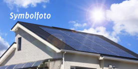 Ein Hausdach mit Solarpanelen und blauen Himmel mit strahlender Sonne. Auf dem Bild steht Symbolfoto geschrieben