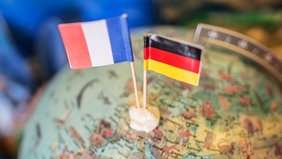 Frankreich- und Deutschlandflagge stecken in Miniaturform in einem Globus