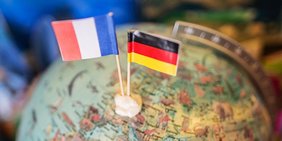Frankreich- und Deutschlandflagge stecken in Miniaturform in einem Globus