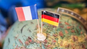 Frankreich- und Deutschlandflagge stecken in Miniaturform in einem Globus