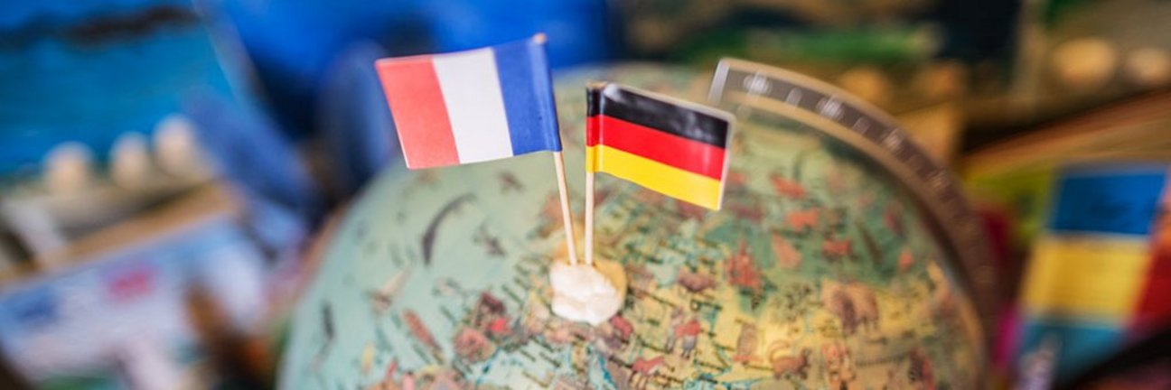 Frankreich- und Deutschlandflagge stecken in Miniaturform in einem Globus