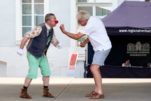 Willi mit Clownsnase auf der Bühne mit einem Mann. Sie spielen als würden sie einen Boxkampf haben.