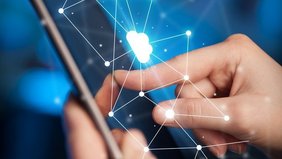 Eine Hand tippt auf ein Tablet vor blauem Hintergrund. Zusätzlich sind verschiedenen Symbole die für eine Cloud stehen 