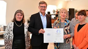 Regionalverbandsdirektor Peter Gillo nimmt die erneute Auszeichnung des Regionalverbands Saarbrücken als „Familienfreundliches Unternehmen“ von Ute Knerr von saar.is entgegen. Gemeinsam mit ihm freuen sich unter anderem Mirjam Altmeier-Koletzki, Frauenbeauftragte und Koordinatorin des lokalen Bündnisses für Familie im Regionalverband (r.) und Kirsten Rosenkranz, Beauftragte für das Betriebliche Gesundheitsmanagement beim Regionalverband (l.) über die Rezertifizierung