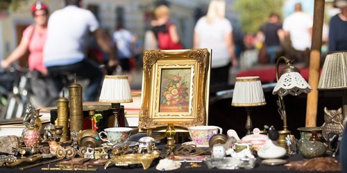 Flohmarktstand mit Verkaufsartikeln, im Hintergrund Menschen die vorbei laufen. 