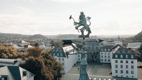 Der Wetterlöwe über Alt-Saarbrücken mit dem Saarbrücker Schloss im Hintergrund