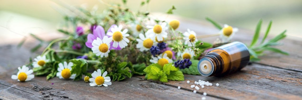 Wildblumenstrauß auf einem Holztisch und nebenan liegt ein Fläschen Globuli