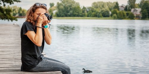 Frau an Flussufer beziehungsweise Steg am Fotografieren