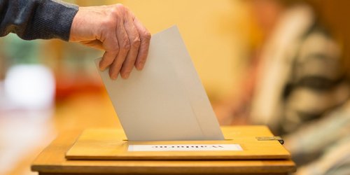 Ein Wahlzettel wird in eine Wahlurne gesteckt