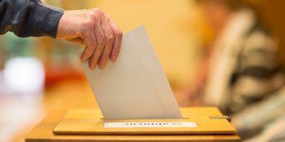 Ein Wahlzettel wird in eine Wahlurne gesteckt