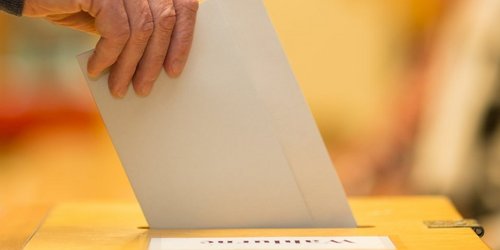 Ein Wahlzettel wird in eine Wahlurne gesteckt