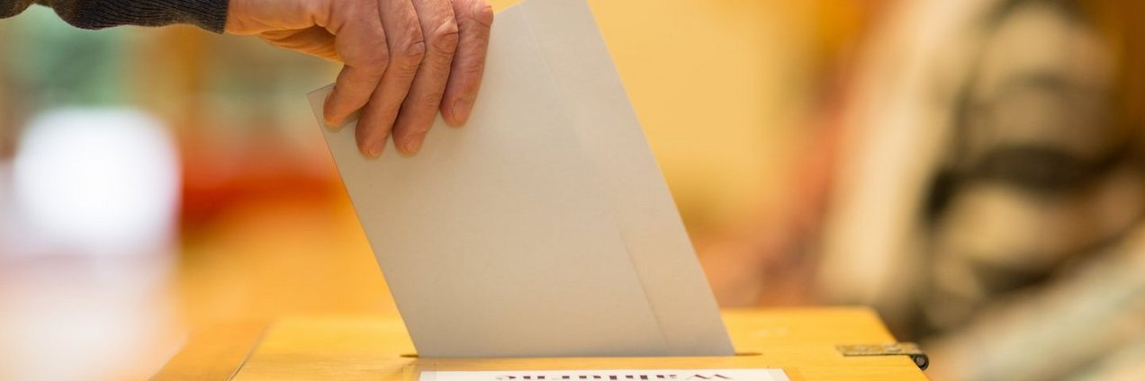 Ein Wahlzettel wird in eine Wahlurne gesteckt