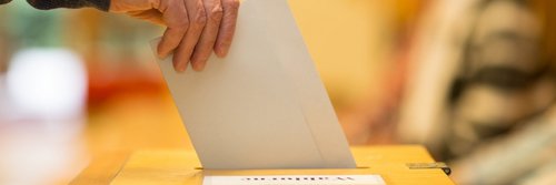 Ein Wahlzettel wird in eine Wahlurne gesteckt