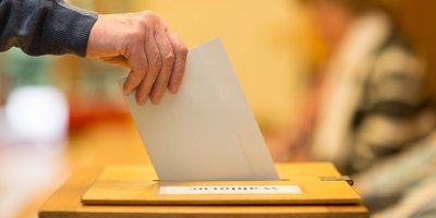 Stimmzettel in Wahlurne Ein Wahlzettel wird in eine Wahlurne gesteckt