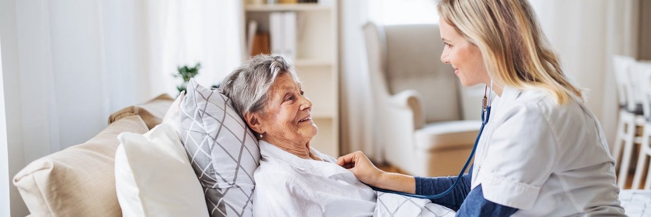 Eine junge Pflegerin kümmert sich um eine Seniorin