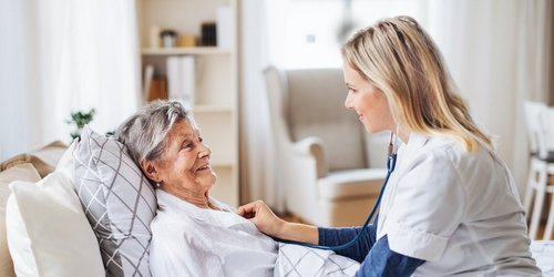 Eine junge Pflegerin kümmert sich um eine Seniorin