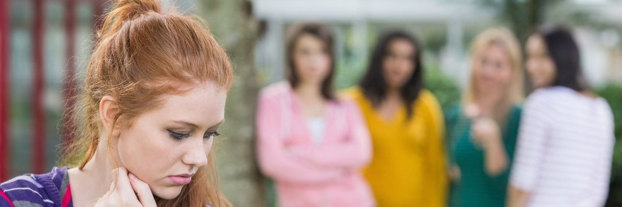 Junge Frau die von einer Gruppe anderer jungen Frauen gemobbt wird