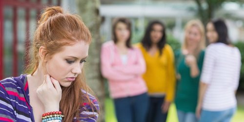 Junge Frau die von einer Gruppe anderer jungen Frauen gemobbt wird