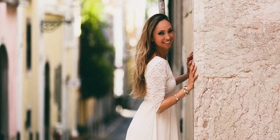 Jeannette Curta Junge Frau lehnt in Gässchen an Hauswand und lächelt