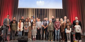 Innenminister Reinhold Jost (l.), Regionalverbandsdirektor Peter Gillo (5.v.l.) und die Bürgermeister von Riegelsberg, Friedrichthal und Kleinblittersdorf sowie die Erste Beigeordnete der Stadt Sulzbach mit den Eingebürgerten im Festsaal des Schlosses, Foto: Alexander Weber/Ministerium für Inneres, Bauen und Sport